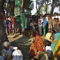 Villagers gather around the bodies of two girls found murdered and hanging from a tree in Uttar Pradesh, India, after they were allegedly gang-raped by four local men, two of whom are police officers. | AP