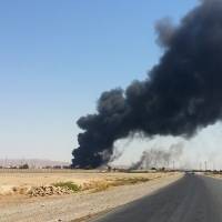 A column of smoke rises from an oil refinery in Beiji, 200 km north of Baghdad, on Thursday amid fierce fighting at the key facility between Iraqi forces and militants of the Islamic State of Iraq and Syria. | AP