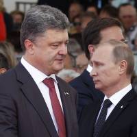 Ukrainian President-elect Petro Poroshenko walks past Russian President Vladimir Putin during an international D-Day commemoration ceremony on the beach of Ouistreham, France, on Friday. Celebrations were held the same day to mark the 70th anniversary of the World War II Allied landings in Normandy. | AFP-JIJI