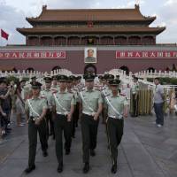 Paramilitary policemen march out of Tiananmen Gate to clear tourists from the area for a May 28 flag-lowering ceremony at Tiananmen Square in Beijing. | AP
