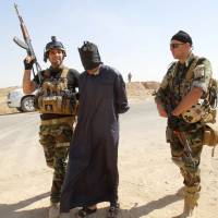 Kurdish security personnel detain a suspected militant from the Islamic State in Iraq and Syria insurgent group outside Kirkuk, Iraq, on Monday. | REUTERS