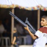 An Iraqi boy holds a weapon Tuesday as he takes part in a gathering of Shiite tribesman showing their willingness to join Iraqi security forces in the fight against ISIS jihadi militants who have taken over several cities in northern Iraq. | AFP-JIJI