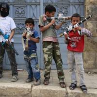 Syrian children pose with their toy weapons in the divided city of Aleppo on Sunday. | REUTERS