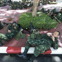 Thai soldiers rest after being deployed at police headquarters to prevent an anti-coup demonstration in Bangkok on Sunday. | AP
