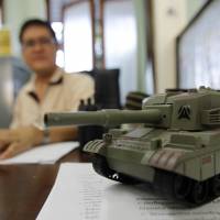 A toy tank is seen on the desk of an official as he works at Government House, after it reopened following a military coup in Bangkok on Monday. | REUTERS