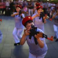 Chinese women holding toy guns dance for a revolutionary song during their daily exercise at a square outside a shopping mall in Beijing on Sunday. | REUTERS