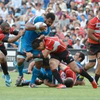 Kick it up a notch: Japan full-back Ayumu Goromaru leads the charges as a group of players converge on Italy\'s Manoa Vosawai (second left) during their match on Saturday. | AFP-JIJI