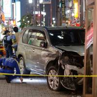 A wrecked car sits on the sidewalk after it struck pedestrians and smashed into a phone booth Tuesday evening in the bustling Ikebukuro district in Toshima Ward, Tokyo. | KYODO