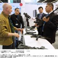 People check out rubber machine guns made for training purposes at the Japan pavilion of the Eurosatory defense fair on Monday in Paris. This is the first international weapons show to see exhibitions by Japanese companies. | KYODO
