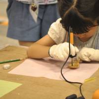 A girl decorates a wooden spoon during a workshop at last year\'s Yokohama Handmade Marche. | REUTERS