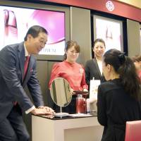 Shiseido Co. President Masahiko Uotani (left) speaks to a customer at Hankyu Department Store\'s Umeda outlet in the city of Osaka on Wednesday as the major cosmetics company released a new skin product strategically developed for the international market. | KYODO