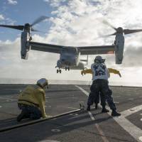 U.S. Navy sailors on July 8 aboard the amphibious dock landing ship USS Rushmore direct an MV-22 Osprey onto the flight deck for a personnel transfer during the at-sea phase of exercise Rim of the Pacific (RIMPAC) 2014. Japan and Israel are believed to be the first nations to purchase the aircraft. | AFP-JIJI