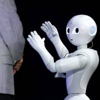 The humanoid robot Pepper, developed by SoftBank Corp.\'s Aldebaran Robotics unit, performs next to Masayoshi Son, chairman and chief executive officer of the telecom giant, at SoftBank World 2014 in Tokyo on Tuesday. | BLOOMBERG