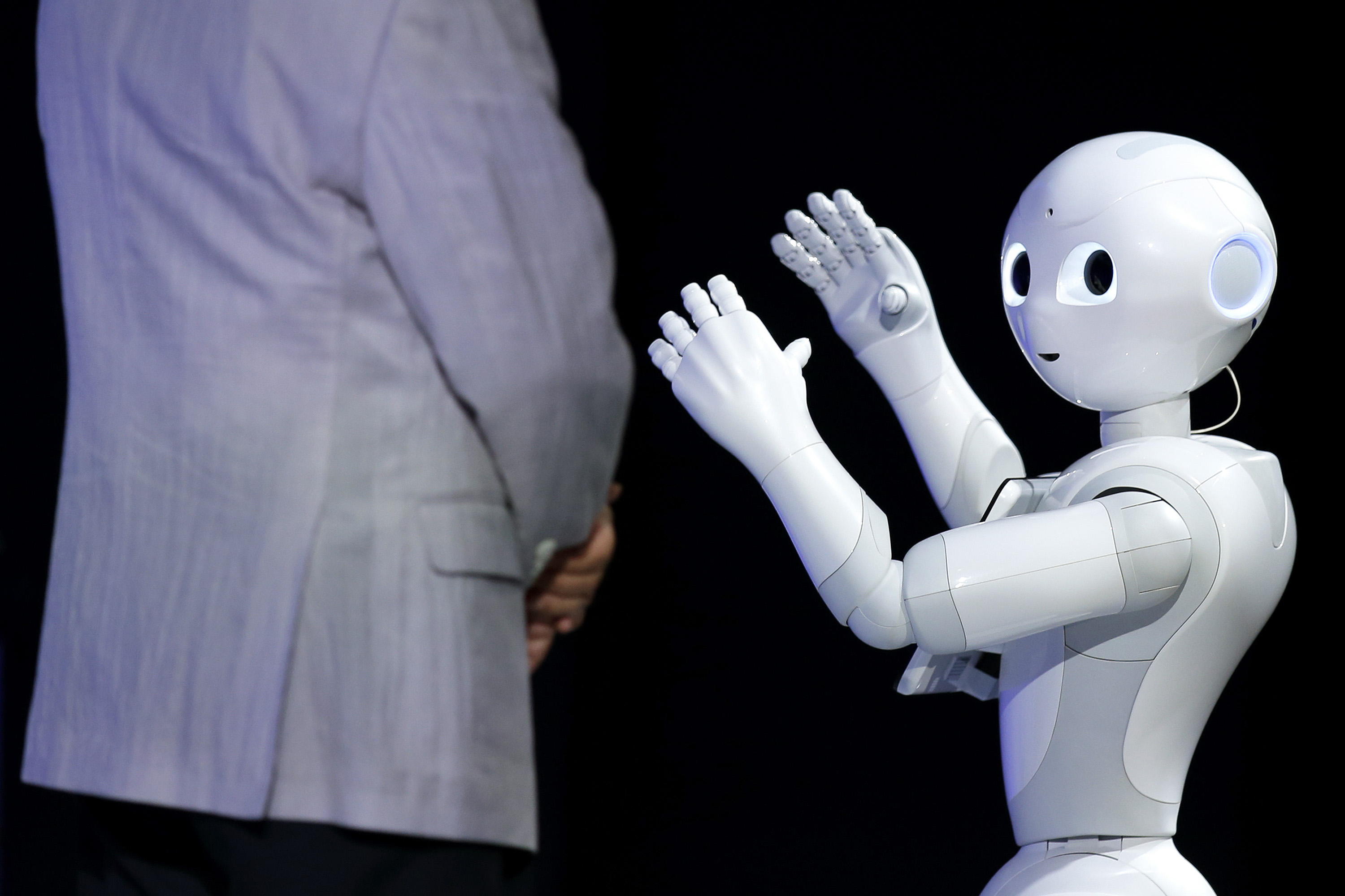 The humanoid robot Pepper, developed by SoftBank Corp.'s Aldebaran Robotics unit, performs next to Masayoshi Son, chairman and chief executive officer of the telecom giant, at SoftBank World 2014 in Tokyo on Tuesday. | BLOOMBERG