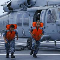 Sailors from the Chinese People\'s Liberation Army (PLA) run after unhooking a U.S. Navy UH60 Seahawk as it prepares to take off from the PLA ship Peace Ark during multinational RIMPAC military drills in Honolulu, Hawaii, on July 23. | REUTERS