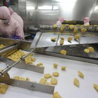 Chicken nuggets roll down a conveyor belt in front of workers at Shanghai Husi Food Co. in Shanghai on Sunday. Shanghai city officials have shut a the Shanghai Husi factory for selling out-of-date meat to restaurant chains including McDonald\'s, KFC and others, authorities said Monday in China\'s latest food safety scandal. | AFP