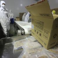 Employees work on a production line prior to a raid by officers from the Shanghai Food and Drug Administration at the Husi Food factory in Shanghai on July 20. | REUTERS