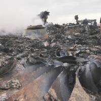 An emergency worker inspects the site of a Malaysia Airlines Boeing 777 plane crash in Ukraine on Thursday. Fatal disaster strikes airline twice