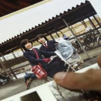 Misa Morimoto, 50, points at a photograph of her older identical twin Miho Yamamoto (left) and herself at a high school graduation ceremony in 1982, at her home in Otsuki, Yamanashi Prefecture, on July 15. | REUTERS