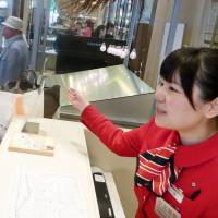 Qian Xiaolei helps foreign shoppers at the Mitsukoshi department store in Tokyo\'s Ginza district in May. | KYODO