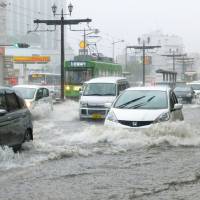 Drivers carefully navigate the flooded streets of Nagasaki on Thursday as heavy rain lashed western Japan. | KYODO