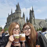 Visitors dressed as characters from the “Harry Potter” book and movie series pose outside the newly opened Wizarding World of Harry Potter at Universal Studio Japan in Osaka on Tuesday.  | KYODO