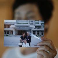 Kim Young-ja holds a photo of her brother, an abductee living in North Korea named Kim Young-nam (right), at her home in Jeonju, South Korea. The photo was taken during a reunion in 2006. | REUTERS