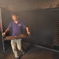 Hiroaki Sakai carries a tray of smoked fillets. | KENJI MIURA
