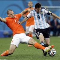 Tough to stop: Argentina’s Lionel Messi tries to avoid a tackle by the Netherlands’ Ron Vlaar in their World Cup semifinal on Wednesday night. Exhausted Dutch unable to find right formula in loss