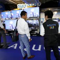 Shoppers look at Sharp Aquos televisions on display at an electronics store in Tokyo on Friday. | REUTERS