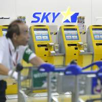An airport worker pushes carts past the Skymark Airlines check-in counter at Narita International Airport on Wednesday morning. | KYODO