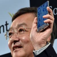 The president of Sharp, Kozo Takahashi, unveils a slender new smartphone called Aquos Crystal, on Monday. It has a 5-inch frameless LCD display and a Harman Kardon audio system. | AFP-JIJI