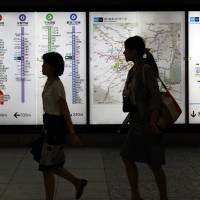 Passengers walk past a Tokyo Metro subway map on July 29. | BLOOMBERG