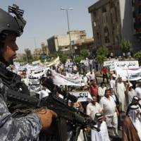 An Iraqi police officer stands guard on Saturday during a demonstration in support of Iraqi Prime Minister Nouri al-Maliki in Baghdad. Al-Maliki\'s largely Shiite supporters took to the streets over the weekend in support of his bid for a third term in office, while clashes between Islamic State militants, Kurdish peshmerga, and Shiite militias continued to ravage the country\'s north. | REUTERS