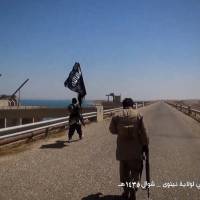 An image taken from video released on Saturday purportedly shows Islamic State militants waving the trademark jihadi flag as they inspect the grounds of the Mosul dam on the Tigris river, about 50 kilometres north of the city. | AFP-JIJI
