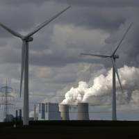 A coal-fired power plant spews emissions behind a pair of wind turbines in Neurath, western Germany, on Feb. 28. Anti-coal dominoes theory hits BRICS wall
