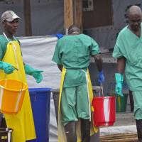 Health care workers in their Ebola virus protective gear are photographed at a treatment center in Monrovia on Monday. | AP