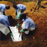 Volunteers lower the corpse of an Ebola victim — prepared according to strict burial guidelines designed to curb contamination risks — into a grave in Kailahun, Sierra Leone, on Saturday. Ebola mortality rate expected to rise as outbreak runs its deadly course