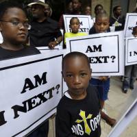 Alvin Duplessis, 10, (left), and Thomas McGriff, 5, (foreground), hold signs with others from the Watson Memorial Teaching Ministries Church of New Orleans at a rally held in the city on July 20, 2014 following the acquittal of George Zimmerman in the shooting death of Trayvon Martin. | AP