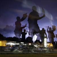 This long-exposure photo shows protesters marching in the street Wednesday in Ferguson, Missouri, as lightning flashes in the distance. | AP