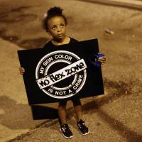 A girl holds a sign Thursday during protests over the shooting of unarmed black teen Michael Brown in Ferguson, Missouri. | AFP-JIJI