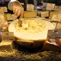 A worker arranges cheese for sale at a grocery store in St. Petersburg on Monday. Moscow initially said it would not stoop to a tit-for-tat response to newly imposed sanctions, but last week it took aim at Western food imports. | REUTERS