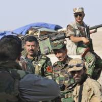 Kurdish peshmerga soldiers stand guard during an intensive security deployment on the outskirts of Sinjar, west of Mosul, on Tuesday. Tens of thousands fled a weekend assault on Sinjar by the Islamic State, and are now surrounded, after the militants inflicted a humiliating defeat on Kurdish forces who had held towns in the area for years. | REUTERS