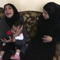 The wife of Lebanese soldier Ali al-Sayyed, who was beheaded by Islamic State militants, holds her daughter as she mourns in the town of Fnideq on Friday. | REUTERS