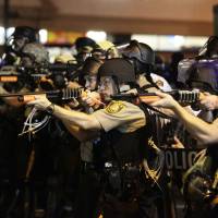 Police officers point their weapons at demonstrators during protests Monday against the shooting death of unarmed black teen Michael Brown by a white police officer on Aug. 9 in the St. Louis suburb of Ferguson, Missouri. As Missouri violence flares, fingers point to outsiders