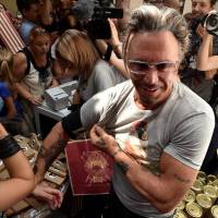 U.S. actor Mickey Rourke stands in front of journalists as he wears a T-shirt with the portrait of Russian President Vladimir Putin in central Moscow on Monday. The sale of a new collection of T-shirts with Putin\'s portrait starts the same day in the city at a price of 1,200 rubles (€25). | AFP-JIJI