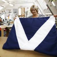 Workers fold a hand-sewn British Union flag (left) and a Scottish St. Andrew\'s or Saltire flag, after completion at the Flagmakers workshop, a unit of Specialised Canvas Services Ltd., in Chesham, U.K., on Friday. A poll of 1,979 voters from across Britain for Sunday newspaper the Observer found 54 percent said they thought Scotland would vote to remain a part of the U.K. and 27 percent that the vote would be in favor of independence. | BLOOMBERG