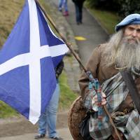 A pro-independence supporter wearing a kilt and holding the Scottish flag attends a rally in Edinburgh last September. | AFP-JIJI