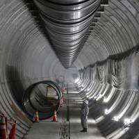 A worker points to the wall of a section of the Furukawa reservoir project being built in central Tokyo on Aug. 7. When completed in 2016, the 3.3-km-long subterranean reservoir will be able to hold 135,000 cu. meters of water, enough to fill 54 Olympic-size swimming pools. | BLOOMBERG