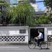 A man cycles past the famous Kira estate in Ryogoku, where, in 1702, a group of 47 wandering samurai from the Ako domain stormed in to assassinate the high-ranking samurai Kira Yoshinaka to avenge the death of Asano Naganori, their master and daimyo of the Ako clan. | SATOKO KAWASAKI